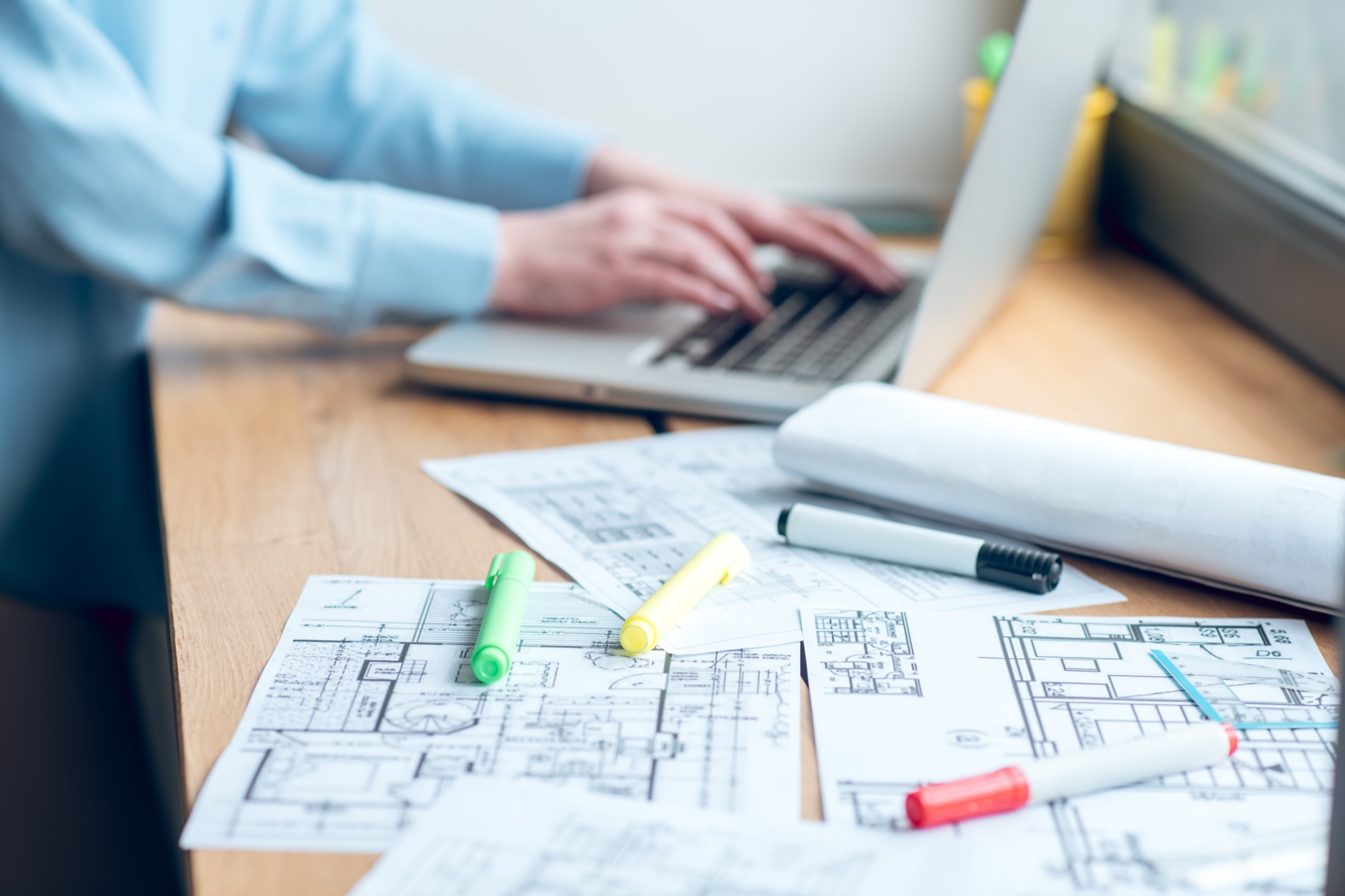 Gutachterlicher Arbeitsplatz mit Bauplänen und Laptop