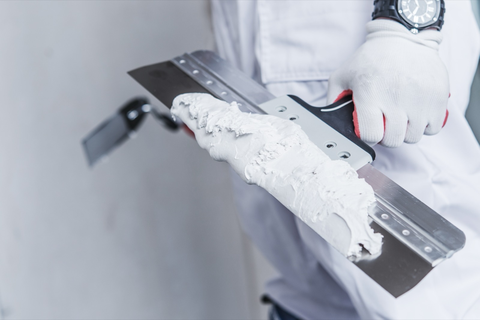 Spachtel mit Füllmasse in der Hand eines Handwerkers